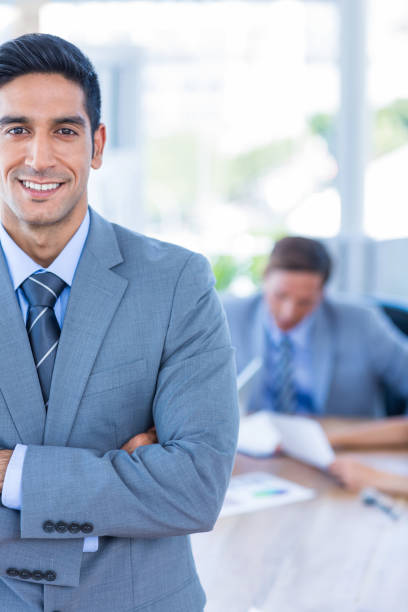 istock Happy businessman looking at camera with his colleagues behind 670232712