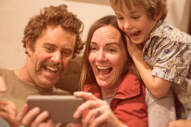Family plays on funny phone app while laughing Family plays on Snapchat together laughing hysterically child laughing hysterically stock pictures, royalty-free photos & images