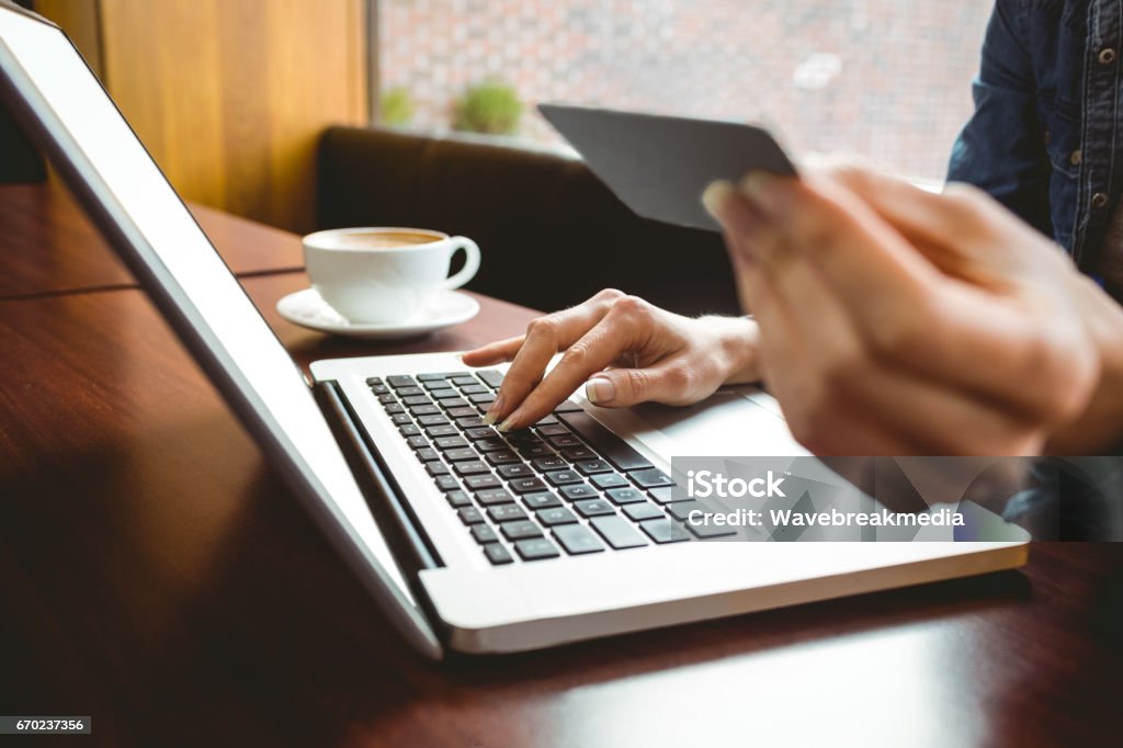 Student using laptop in cafe to shop online Student using laptop in cafe to shop online at the university Credit Card Stock Photo