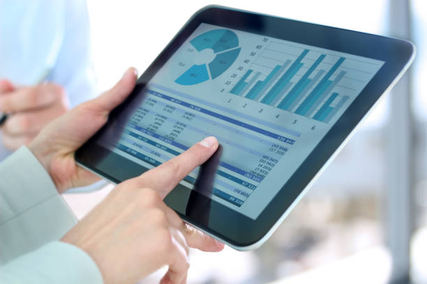 businesswoman showing graphs by finger at the digital tablet stock photo