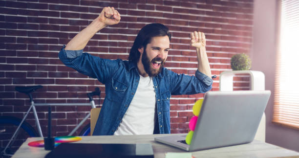 istock Cheerful creative businessman with arms raised looking at laptop 670247090