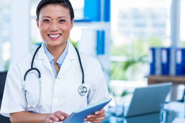 istock Happy doctor smiling at camera holding tablet 670262740