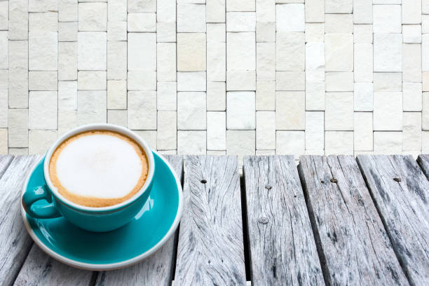 istock Cappuccino on the wooden table and Stacked stone wall background. 670266168