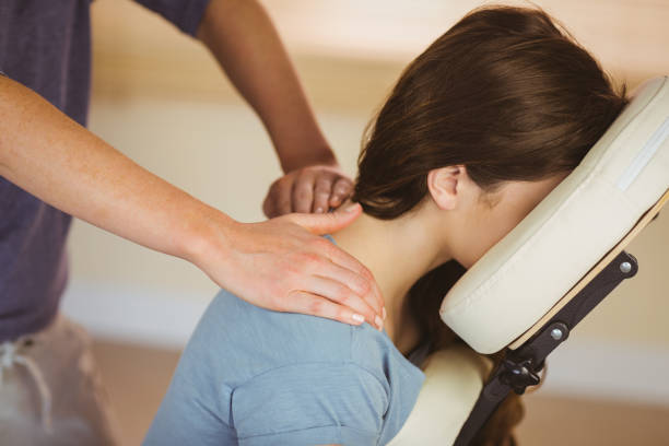 jonge vrouw krijgt massage in stoel - massage stockfoto's en -beelden
