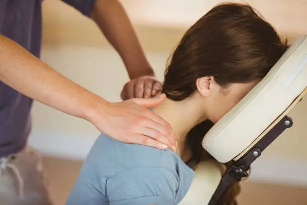 Photo of Young woman getting massage in chair