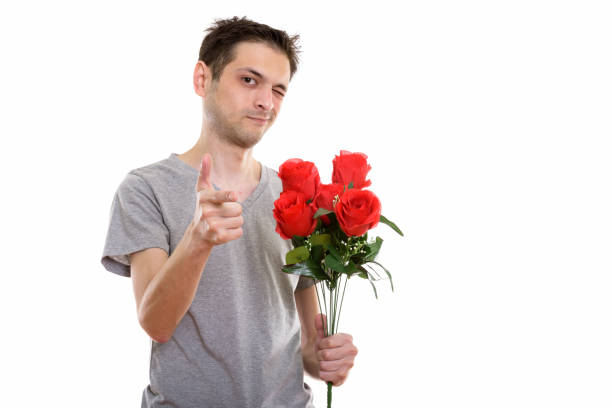 istock Studio shot of young man holding red roses while pointing at camera and winking ready for Valentine's day 670271930