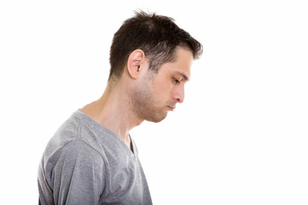 Profile view of sad young man looking down Profile view of sad young man looking down horizontal shot frowning headshot close up studio shot stock pictures, royalty-free photos & images