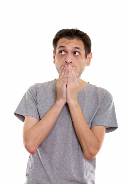 istock Studio shot of young man looking shocked while covering mouth and thinking 670272236