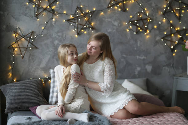 istock Mom and daughter under rug on bed communicate hug 670275712