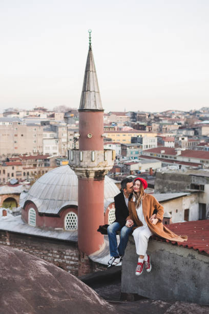 couple in love sitting  on roof with view of evening istanbul. casual style, autumn look, red beret and beige coat - sexual issues sexual activity couple tan imagens e fotografias de stock