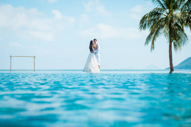 newly married couple after wedding in luxury resort. romantic bride and groom relaxing near swimming pool. honeymoon. - honeymoon beach swimming pool couple imagens e fotografias de stock
