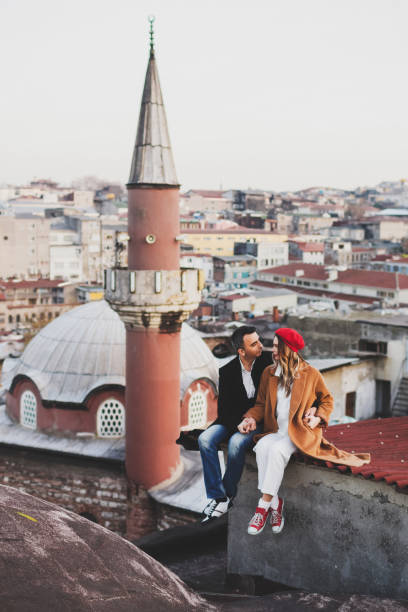 couple in love sitting  on roof with view of evening istanbul. casual style, autumn look, red beret and beige coat - sexual issues sexual activity couple tan imagens e fotografias de stock
