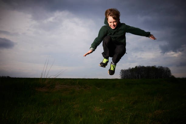 istock Child blond boy jumping in a spring green meadow 670280890