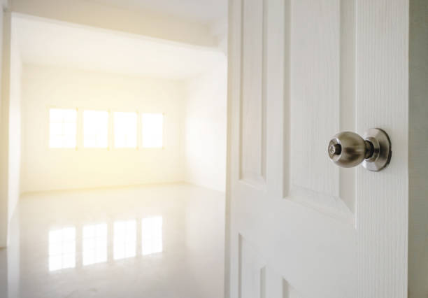 Close-up opened door with empty white room space, and bright light from window