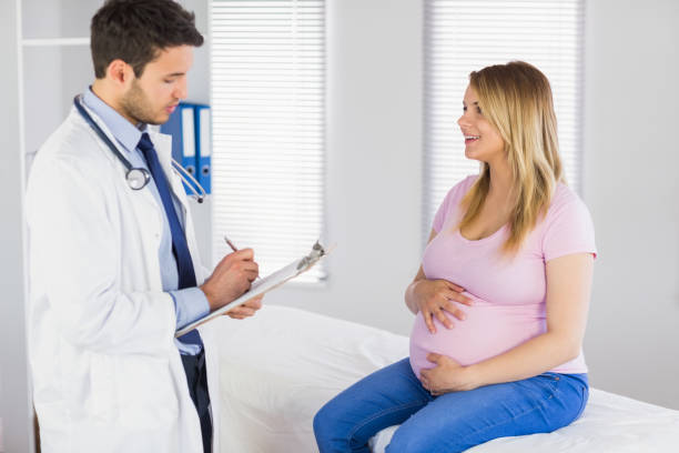 istock Smiling pregnant patient talking to doctor which is taking notes 670314994