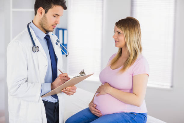 istock Smiling pregnant patient talking to doctor which is taking notes 670315170