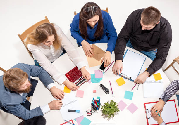 istock Team sitting behind desk, checking reports, talking. Top View 670321208