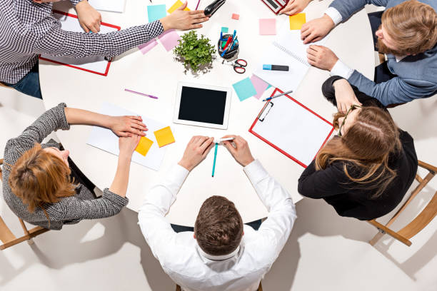 istock Team sitting behind desk, checking reports, talking. Top View 670321292