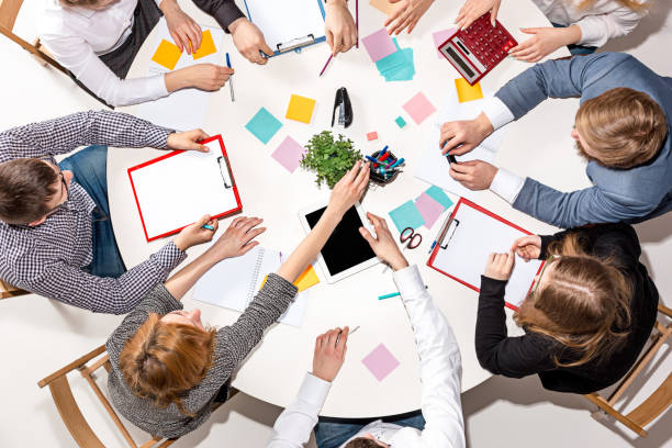 istock Team sitting behind desk, checking reports, talking. Top View 670325750