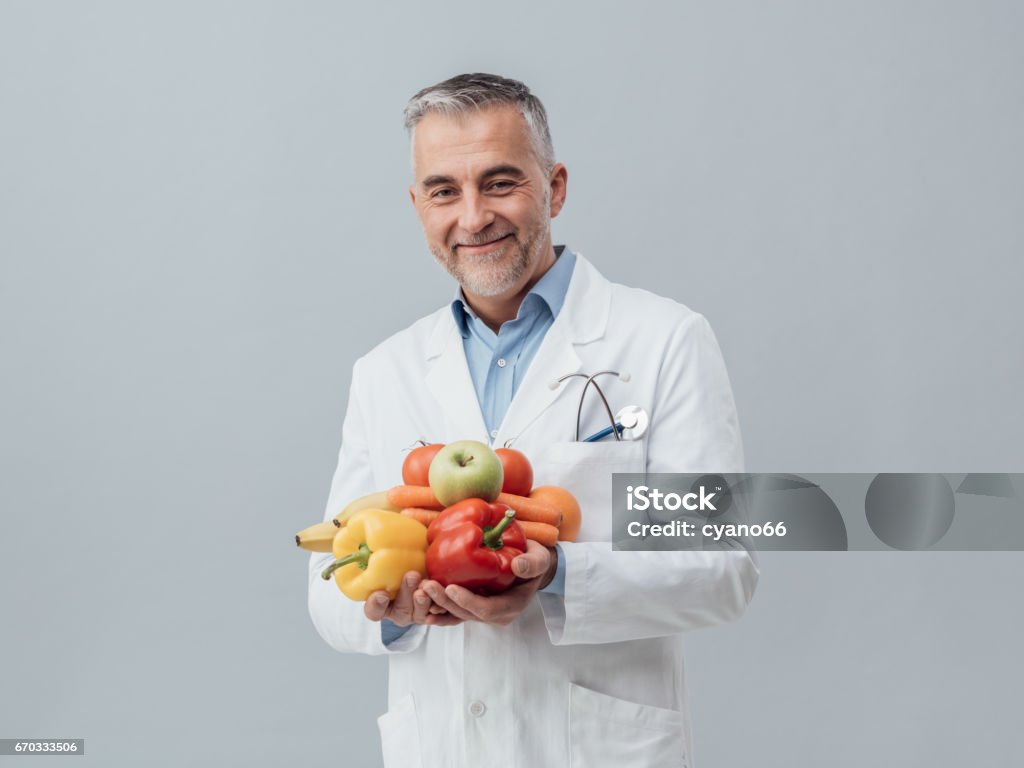 Smiling nutritionist holding fresh vegetables and fruit Smiling nutritionist holding fresh vegetables and fruit: healthcare and healthy vegetarian diet concept Nutritionist Stock Photo