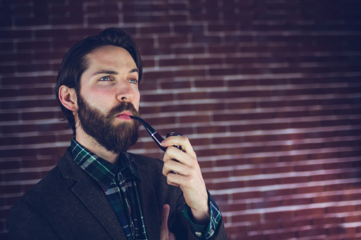 A Handsome man smoking a old pipe