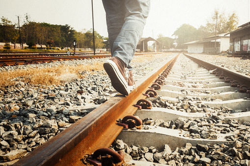 Travel and Relax copyspace background concept. Female legs in sneakers on the rail of the railway.