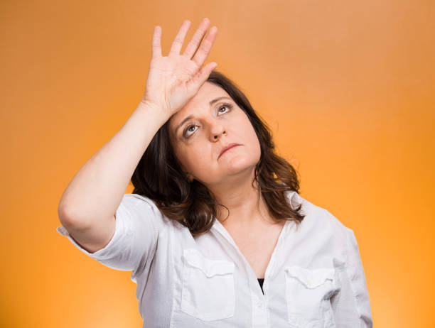 annoyed tired middle aged woman placing back hand on forehead - only women flash imagens e fotografias de stock