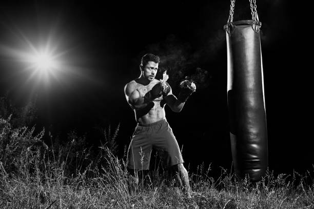 istock Professional boxer punching sandbag outdoors with his boxing glo 670350208