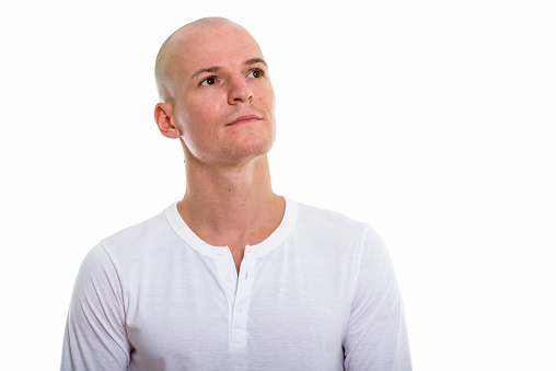 Studio shot of young handsome bald man thinking while looking up horizontal shot