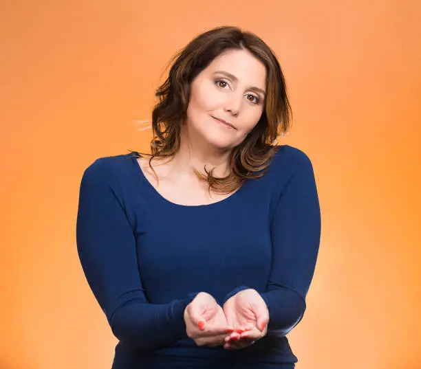Portrait young, middle aged smiling, happy, kind woman with raised up palms arms at you offering something, isolated orange background. Positive emotion facial expression sign symbol