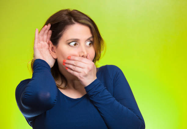 Portrait curious, nosy woman carefully listening to someone's conversation, gossip hand to ear gesture Portrait curious, nosy woman carefully listening to someone's conversation, gossip hand to ear gesture, covering mouth, shocked by discovered, planning revenge, isolated green background. Face expressions, body language funny pregnancy announcements stock pictures, royalty-free photos & images