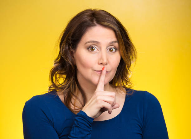 istock Female showing hand silence sign, making shushing gesture holding her index finger to lips 670358896