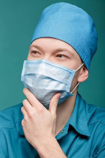 istock male surgeon in mask on blue background, close up 670359606