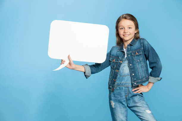 istock Smiling little girl with hand on hip holding speech bubble on blue 670370066