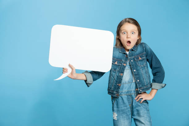 istock Shocked little girl holding blank speech bubble on blue 670370472
