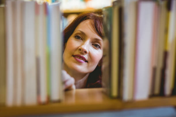 istock Mature student picking out book in library 670374382
