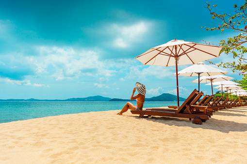Woman in sunhat sunbathing in beach chair