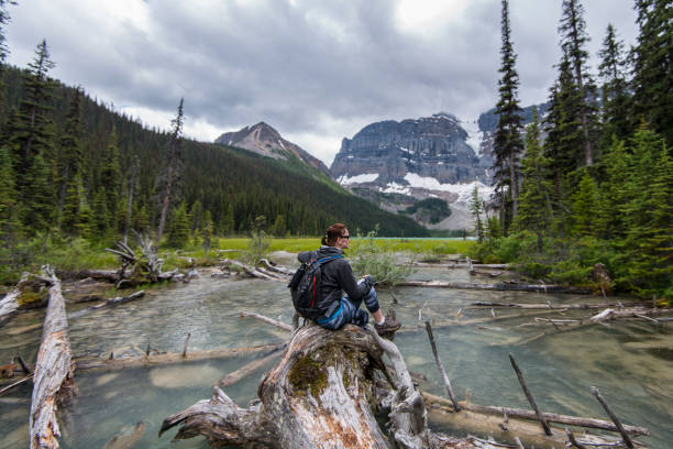 istock Hiker rests on log in mountain stream 670383215