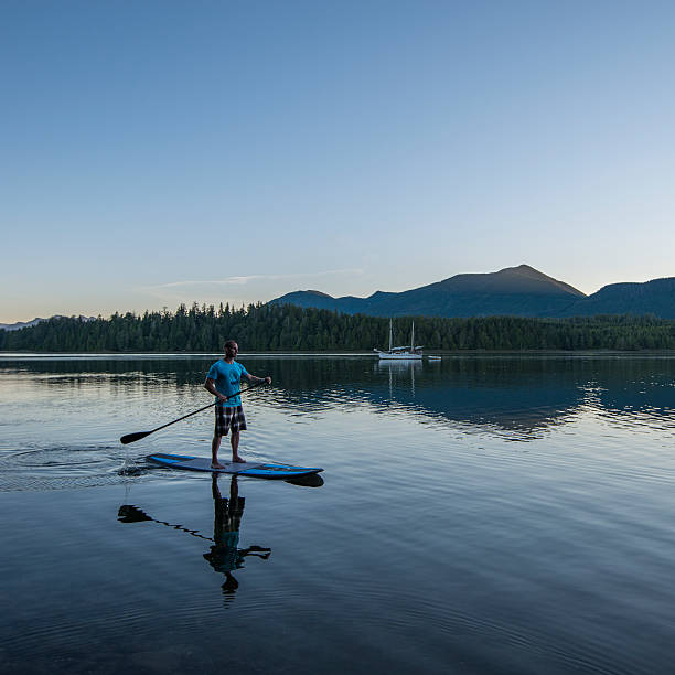 istock Man pilots stand up paddle board, ocean lagoon 670383233