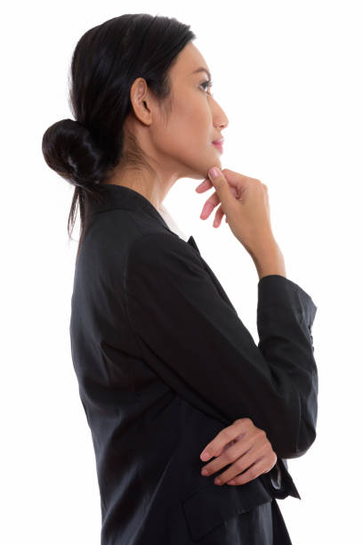 Profile view of young beautiful Asian businesswoman thinking Profile view of young beautiful Asian businesswoman thinking vertical shot hand on chin stock pictures, royalty-free photos & images