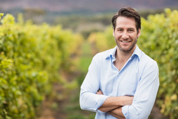 Happy vintner with crossed arms in the fields