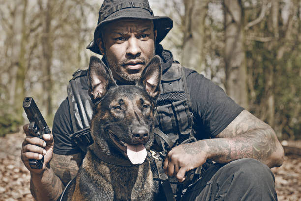 istock Handsome black middle aged security agent working with guard dog in woodlands 670387118