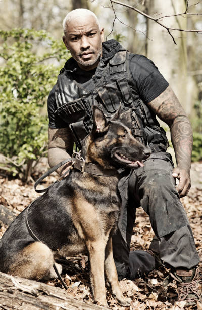 istock Handsome black middle aged security agent working with guard dog in woodlands 670387232