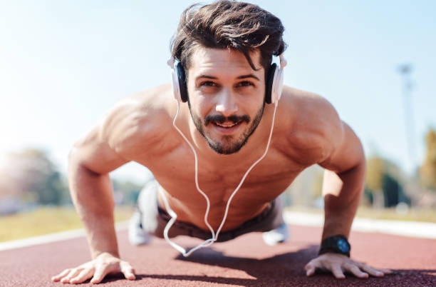 push-ups. jeune sportif musculaire, faire des exercices de remise en forme à l’extérieur. sport, fitness, concept d’entraînement rue - headphones relaxation outdoors caucasian photos et images de collection