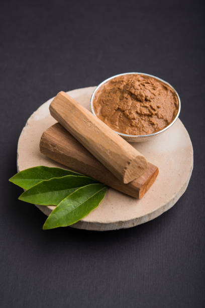 polvere di chandan ayurvedica o pasta di sandalo in ciotola d'argento con bastoncini e foglie posti sopra sahan o sahana o base circolare in pietra per creare pasta - legno di sandalo foto e immagini stock