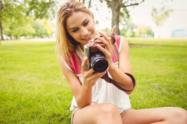 istock Smiling woman looking at camera while sitting on grass 670393976