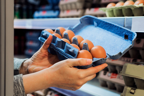 Woman chooses packing chicken eggs in the supermarket, Eggs preserved in woman hand and panel wholesale market,