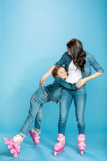 istock mother and daughter in roller skates hugging in studio on blue 670400958