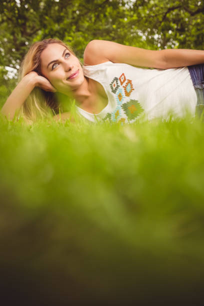 istock Happy woman looking away while relaxing on grass 670402170