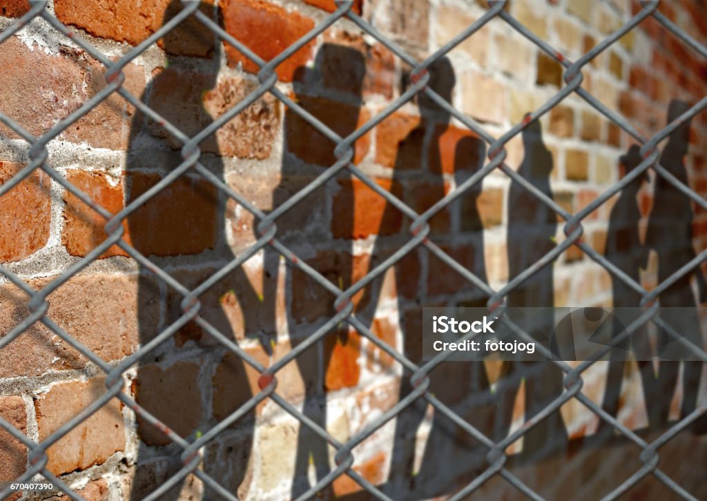 People shadows Shadows of people on a wall behind a fence Prison Stock Photo
